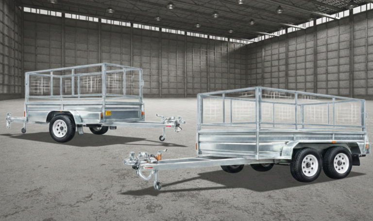 Two galvanized utility trailers displayed in a spacious industrial setting, highlighting their sturdy construction and practical design for hauling goods.